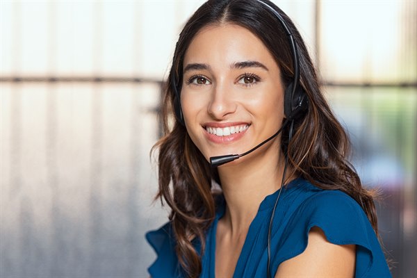 En kvinna med ett headset ler in i kameran. Bild.