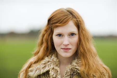 Young red-haired woman looks into the camera.