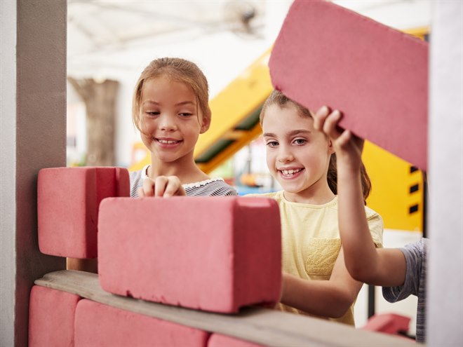 Barn bygger en vägg med lektegelstenar.