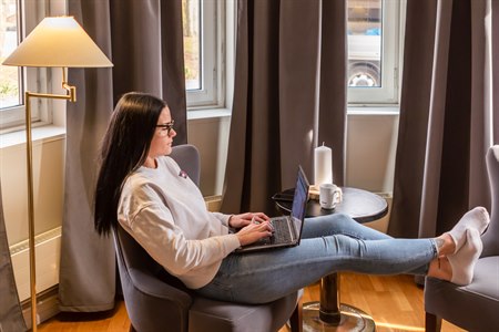 A woman in a chair with a pc on her lap. Image.