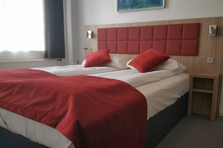 Triple hotelværelse med rød indretning. Bilde.