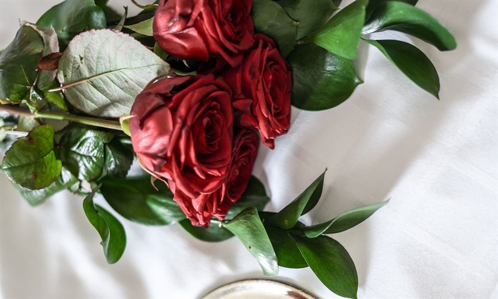Roses and chocolate pralines on a bed.
