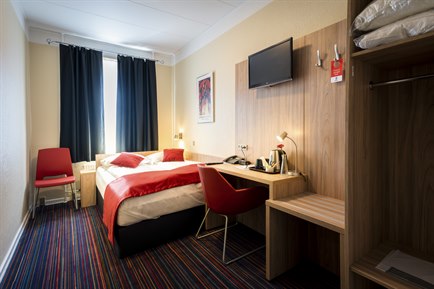 Small double room with red furniture. Photo.