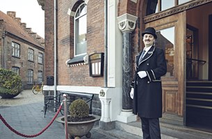 A concierge stands outside the hotel entrance. Photo.