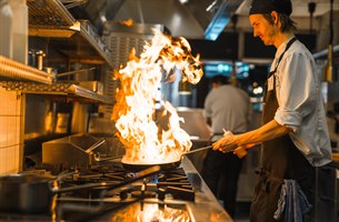 Kokk flamberer mat i restauranten