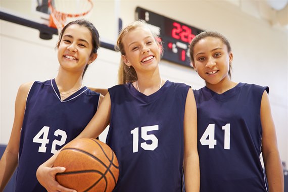 Tre basketballpiger smiler til kameraet. Billede.