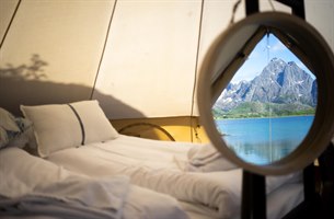 Säng i tält med utsikt över Lofoten. Foto.