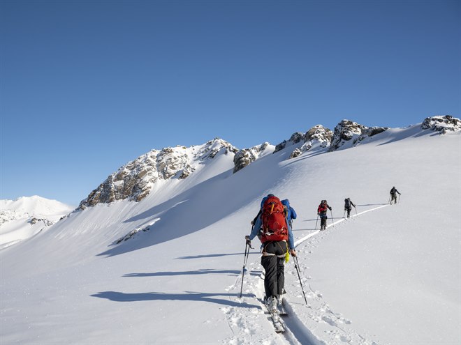 Ski mountaineers going up a snowy mountain.