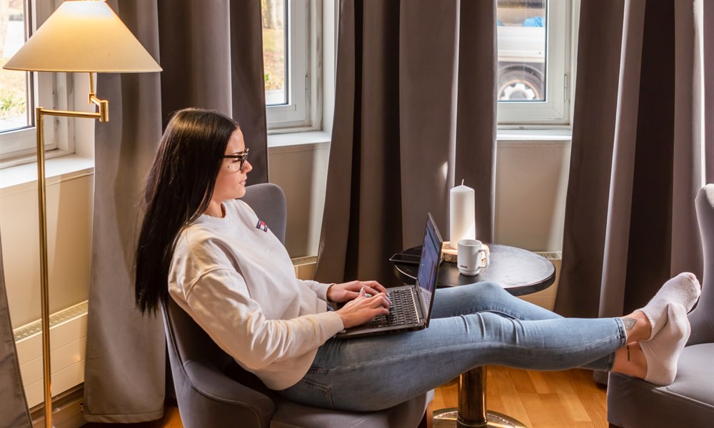 A woman in a chair with a pc on her lap. Image.