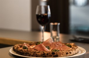 A pizza and a glass of wine. Image.