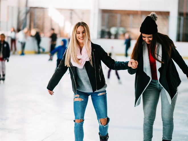Två tjejkompisar åker skridskor inomhus.