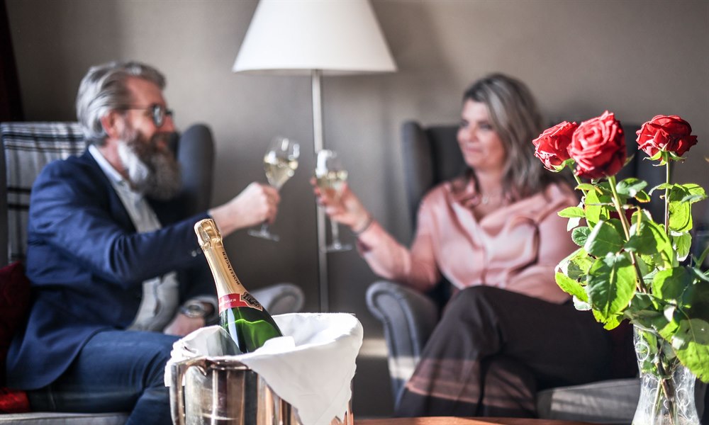 Two people in each armchair and a bottle of bubbly.