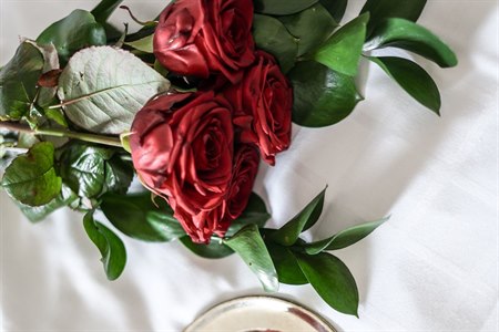 Roses and chocolate pralines on a bed.