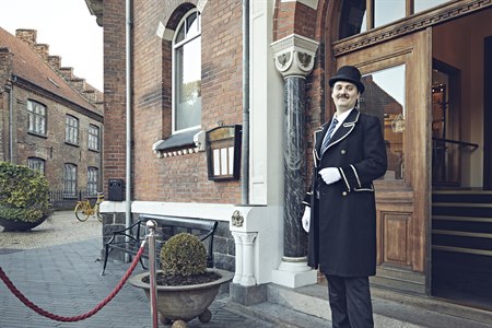 En concierge står uden for hotellets indgang. Foto.