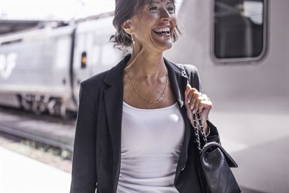 En smilende kvinne på en togstasjon. Bilde.