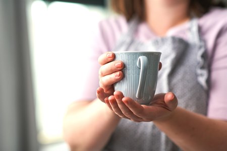 A person holding a cup. Image.