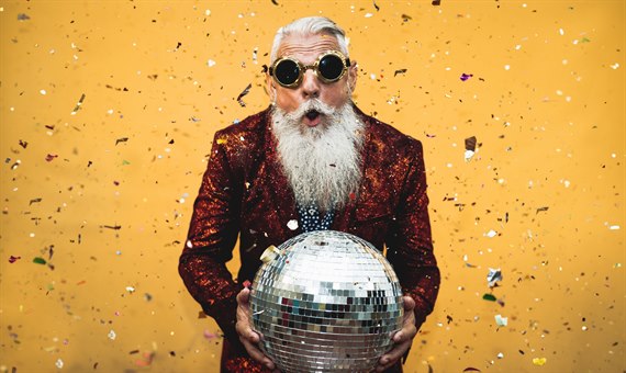 Senior man with sunglasses holding a disco ball surrounded with confetti. Image.