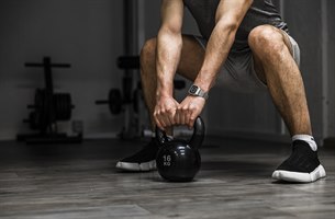 A man is holding a kettlebell. Image.
