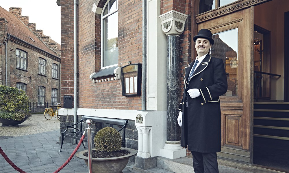 En concierge står uden for hotellets indgang. Foto.