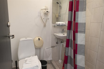Bathroom with strip color curtain. Photo.