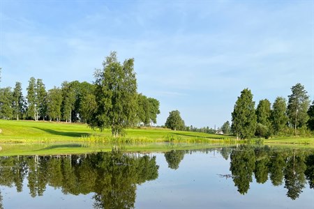 Fin golfbane med liten innsjø. Bilde.