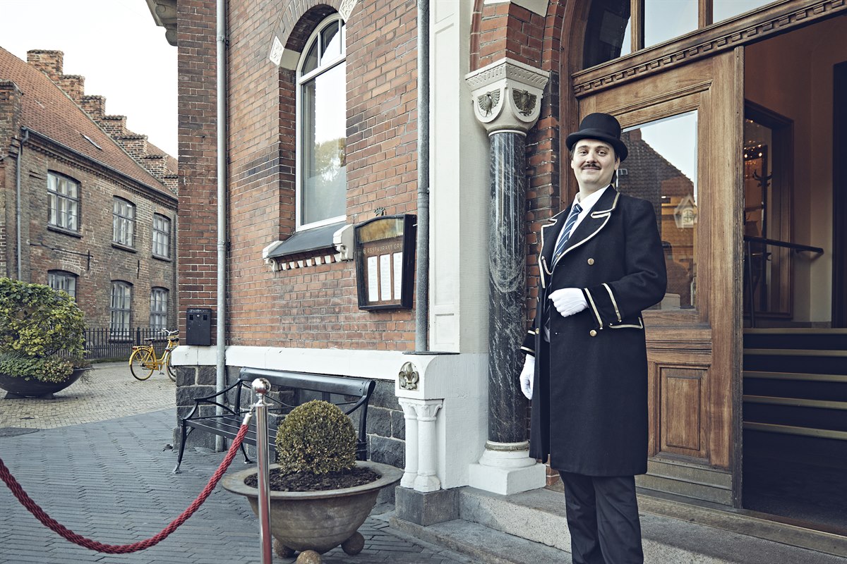 En concierge står utenfor hotellinngangen. Foto.