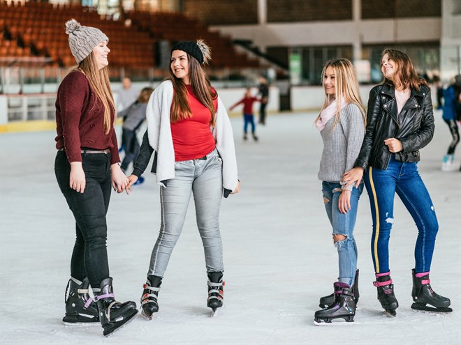 Vänner har roligt med skridskoåkning inomhus.